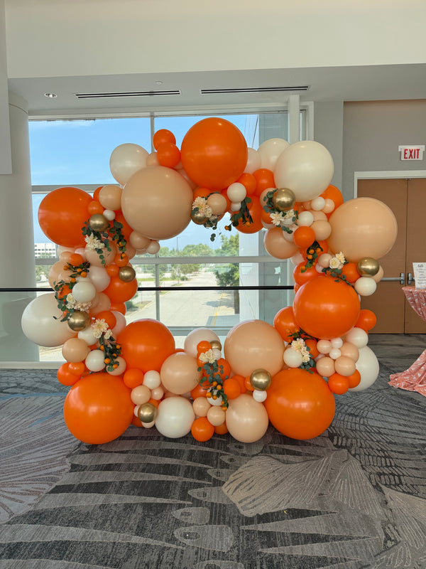 Balloon arch with orange, white, and gold balloons in an indoor setting in Chicago.