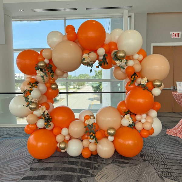 Balloon arch with orange, white, and gold balloons in an indoor setting in Chicago.