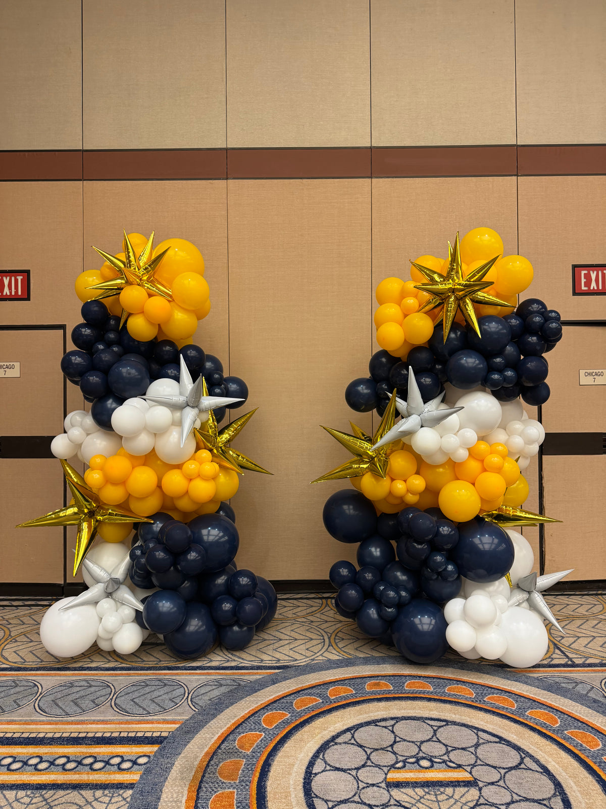 Decorative balloon arrangement in navy, yellow, and white on a wall.