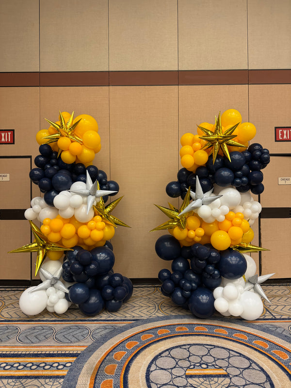 Decorative balloon arrangement in navy, yellow, and white on a wall.